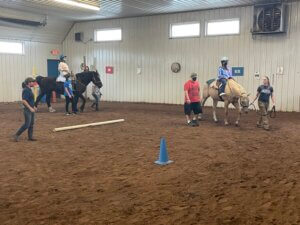 girls riding horses in an indoor rink with staff